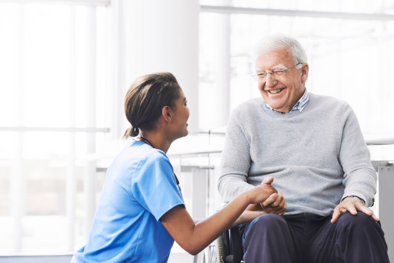 nurse talking to elderly man in a wheelchair